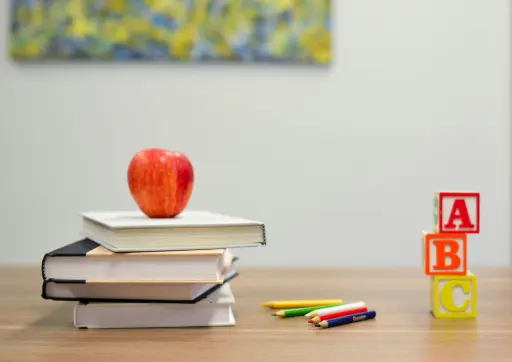 Red apple on some books, with pencils and blocks